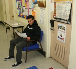 Student waits outside the school counselor’s office to discuss AP Testing options. They read literature concerning the multple tests they have the choice of taking, payment options and parent-student contracts. 