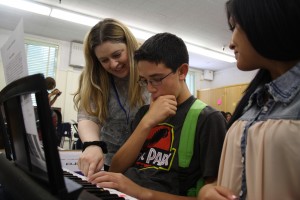 Photo by Ana Perez. Music teacher Jackie Gorski shows students Rudy Calderon and Karla Medrano how to play a piece on the pianos she recently received through online donations.