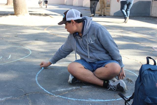 Sophomore Pedro Morataya completes his circle in honor of Pi Day in the math courtyard. 