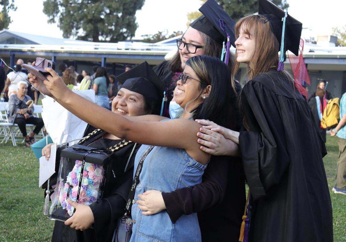 Graduates Lauren Galvez, Nigel Donohue and Desiree Spurkel take a photo with sophomore Aischelle Baun during the graduation ceremony on June 11.