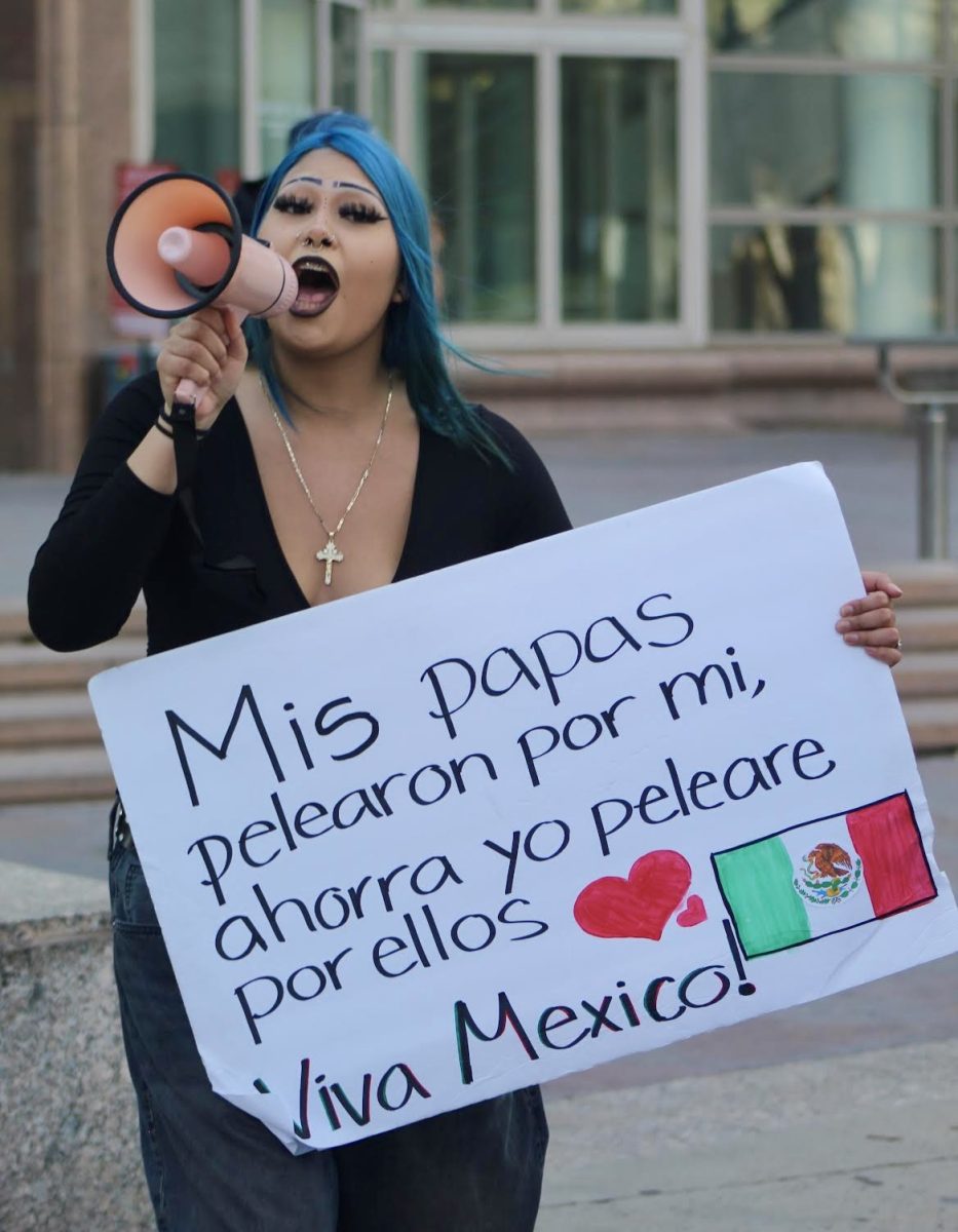 Junior Delilha Trujillo yells into a megaphone while holding a sign on Feb. 10. The sign mentioned how she will fight for her parents after they fought for her.