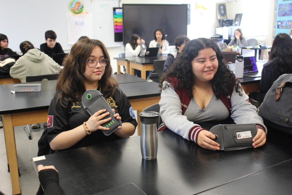 Juniors Ariana Lopez Villacorta and Nemesi Morales hold up their Yandr pouches during their period 2 AP Environment Science class on Feb. 18. The district wide cellphone ban was implemented on Feb. 18. 